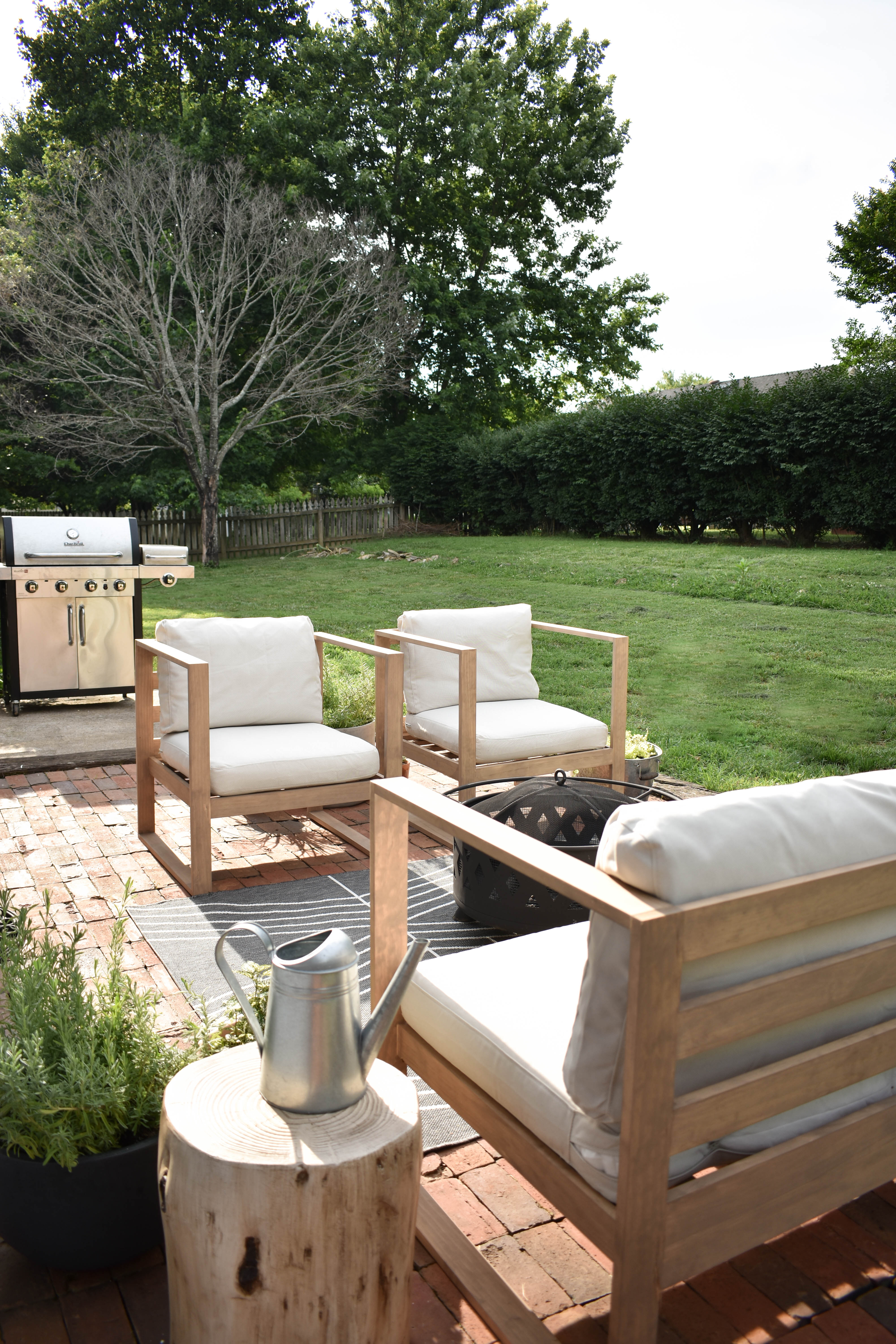 back patio with modern outdoor furniture chairs, sofa and black fire pit